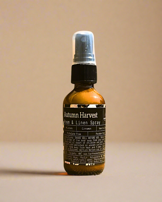 Bottle of Autumn Harvest room and linen spray by Farmhouse Charm Candles on a beige  background