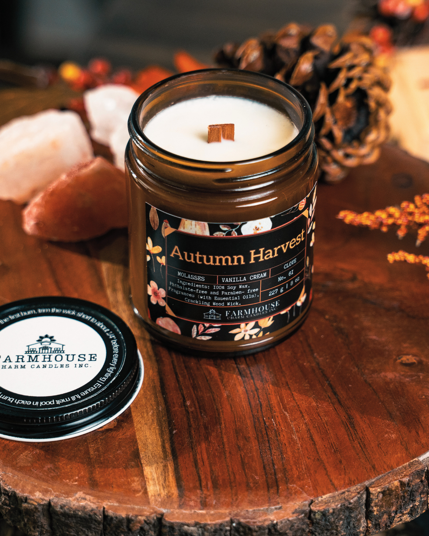 Soy Candle labeled 'Autumn Harvest' by Farmhouse Charm Candles on a wooden surface with fall decorative elements.