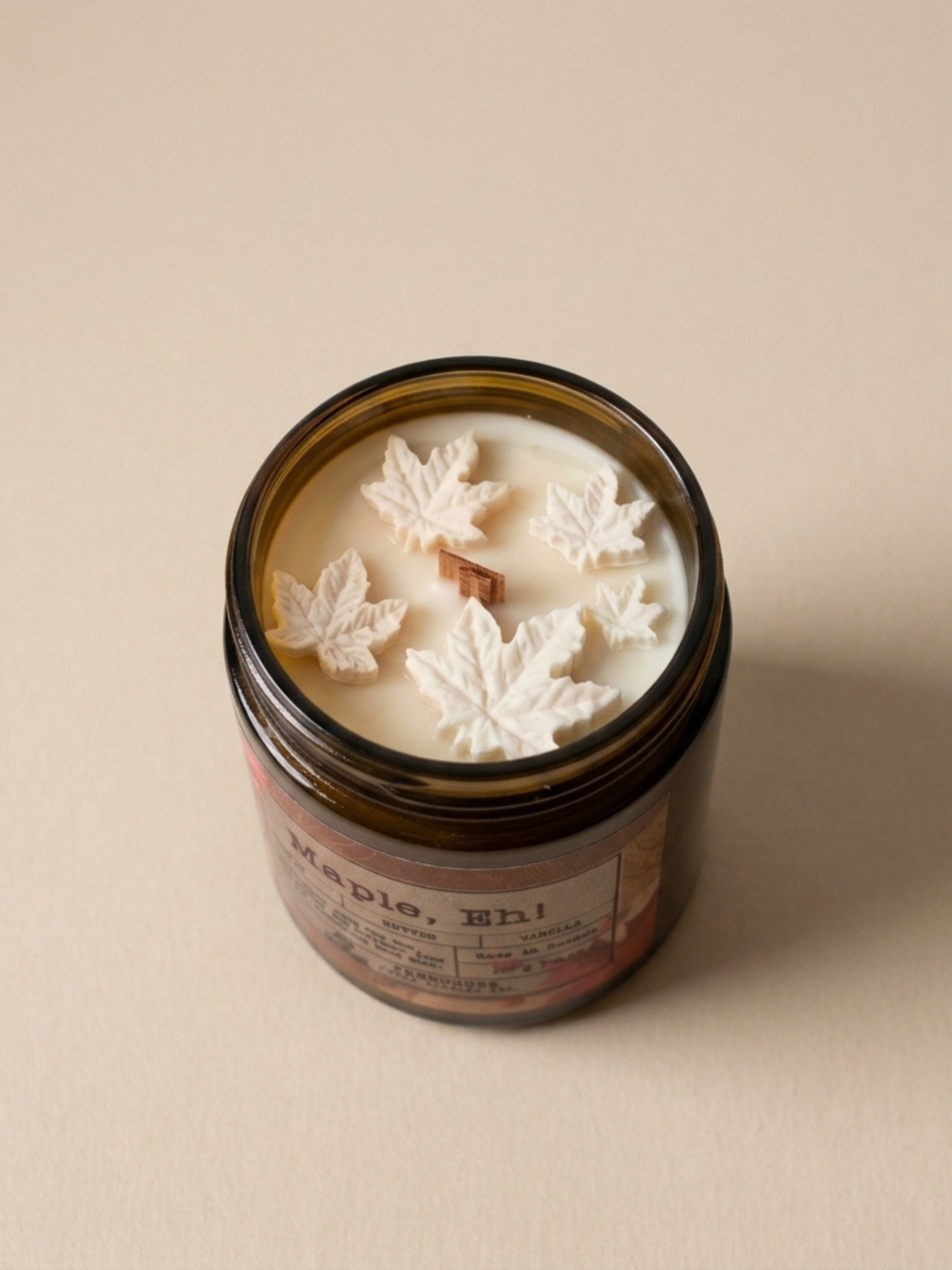 Candle jar with leaf-shaped wax pieces on a beige background. Maple, Eh Soy Candle by Farmhouse Charm Candles