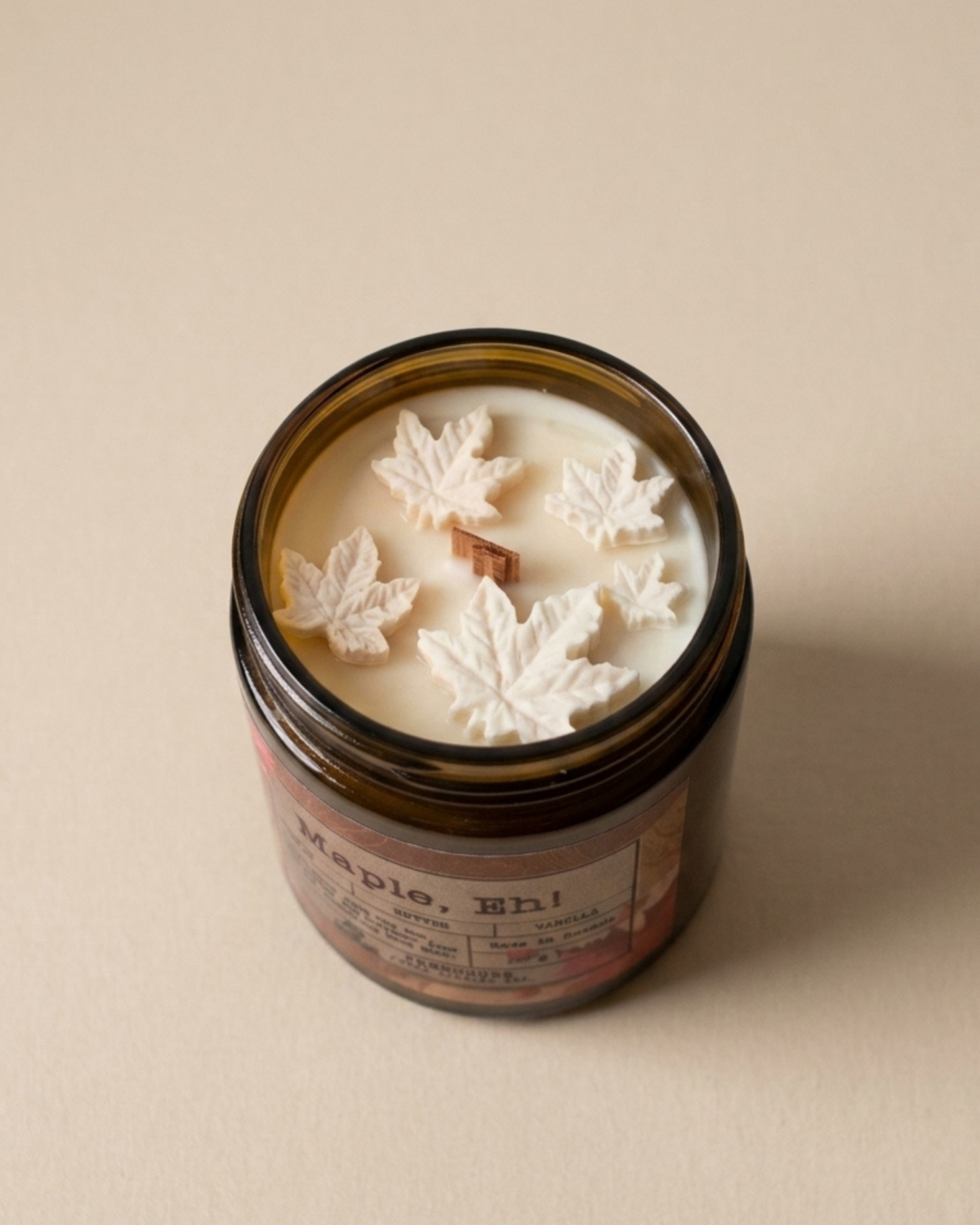 Candle jar with leaf-shaped wax pieces on a beige background. Maple, Eh Soy Candle by Farmhouse Charm Candles