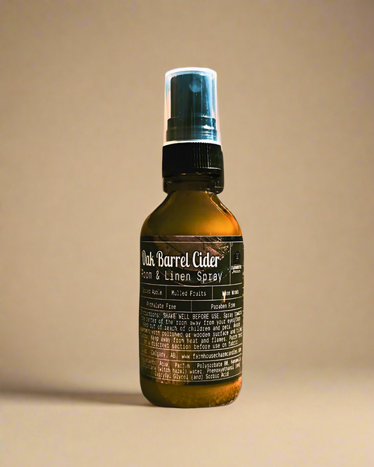 Bottle of Oak Barrel Cider Room & Linen Spray by Farmhouse Charm Candles on a beige background