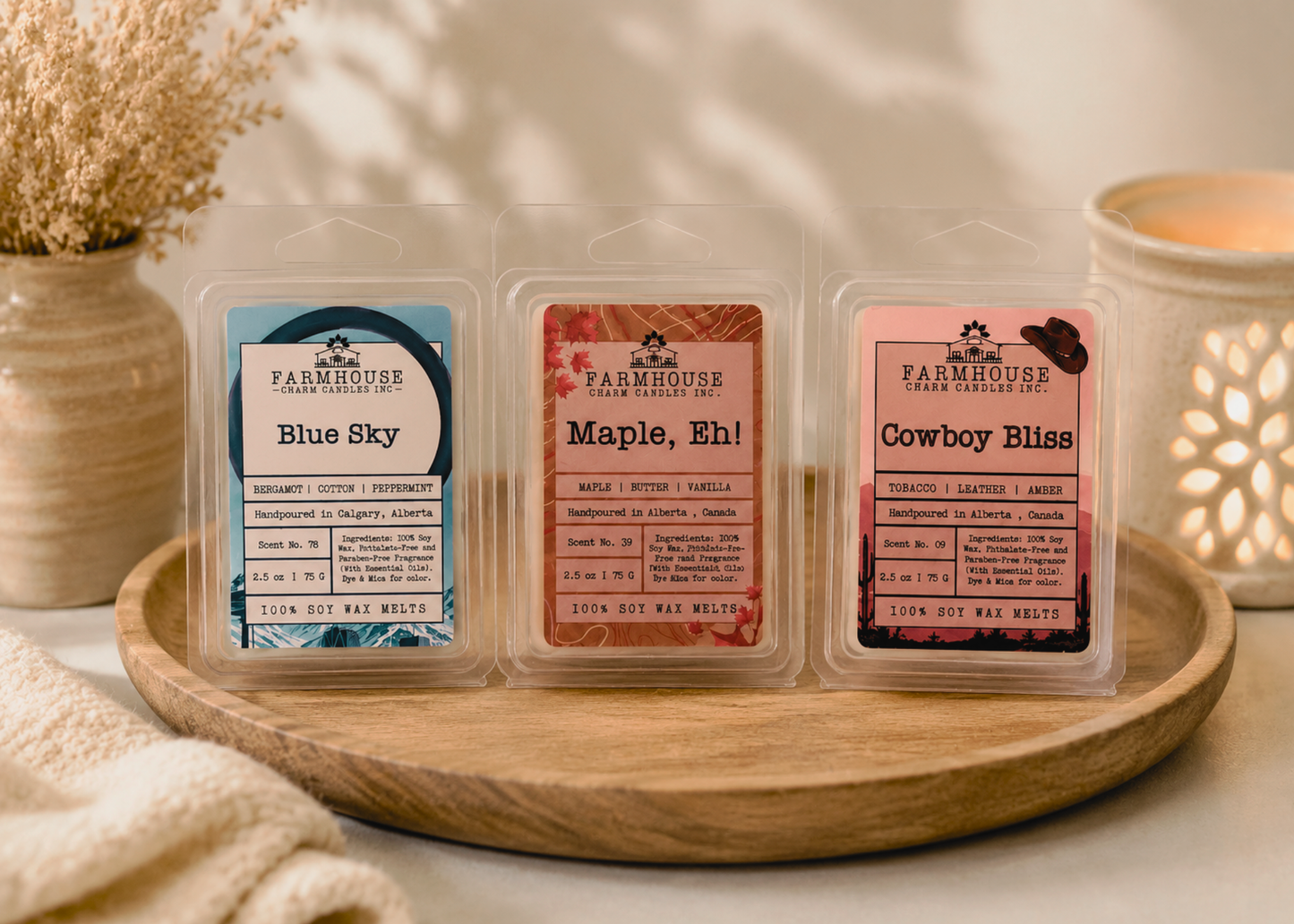 Oh Canada Wax Melts Bundle — Blue Sky, Maple Eh and Cowboy Bliss soy wax melt clamshells displayed on a round wood tray with a glowing wax warmer, dried pampas grass and linen cloth — Farmhouse Charm Candles