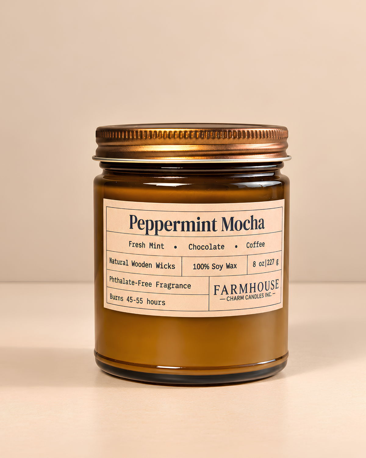 A candle in a brown glass jar with a gold metal lid and a cream-colored label that reads 'Peppermint Mocha' by 'Farmhouse Charm Candles on a warm beige background.
