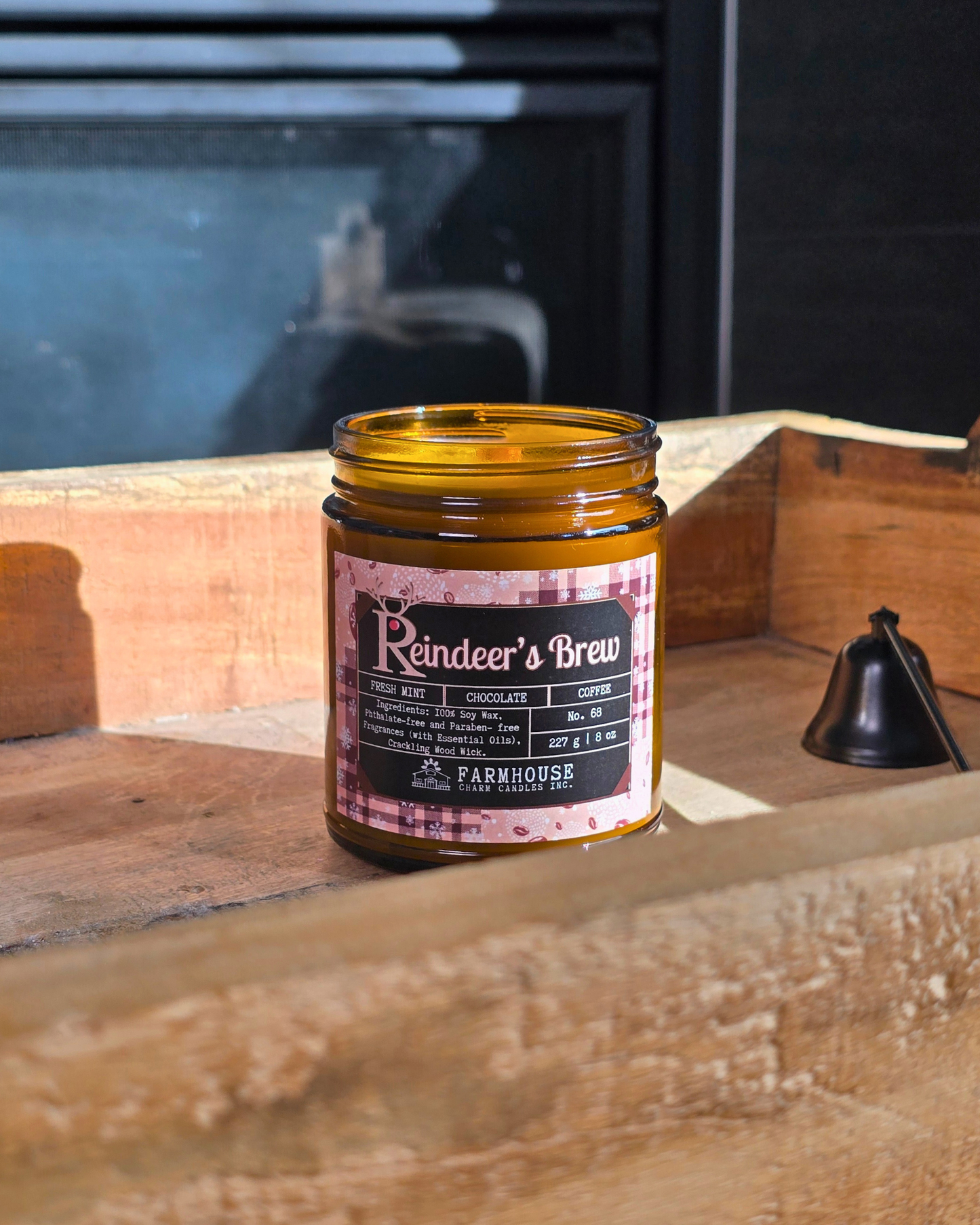 Reindeer’s Brew soy candle in amber jar with warm holiday glow, surrounded by coffee beans, peppermint, and chocolate pieces — cozy Christmas scent from Farmhouse Charm Candles.