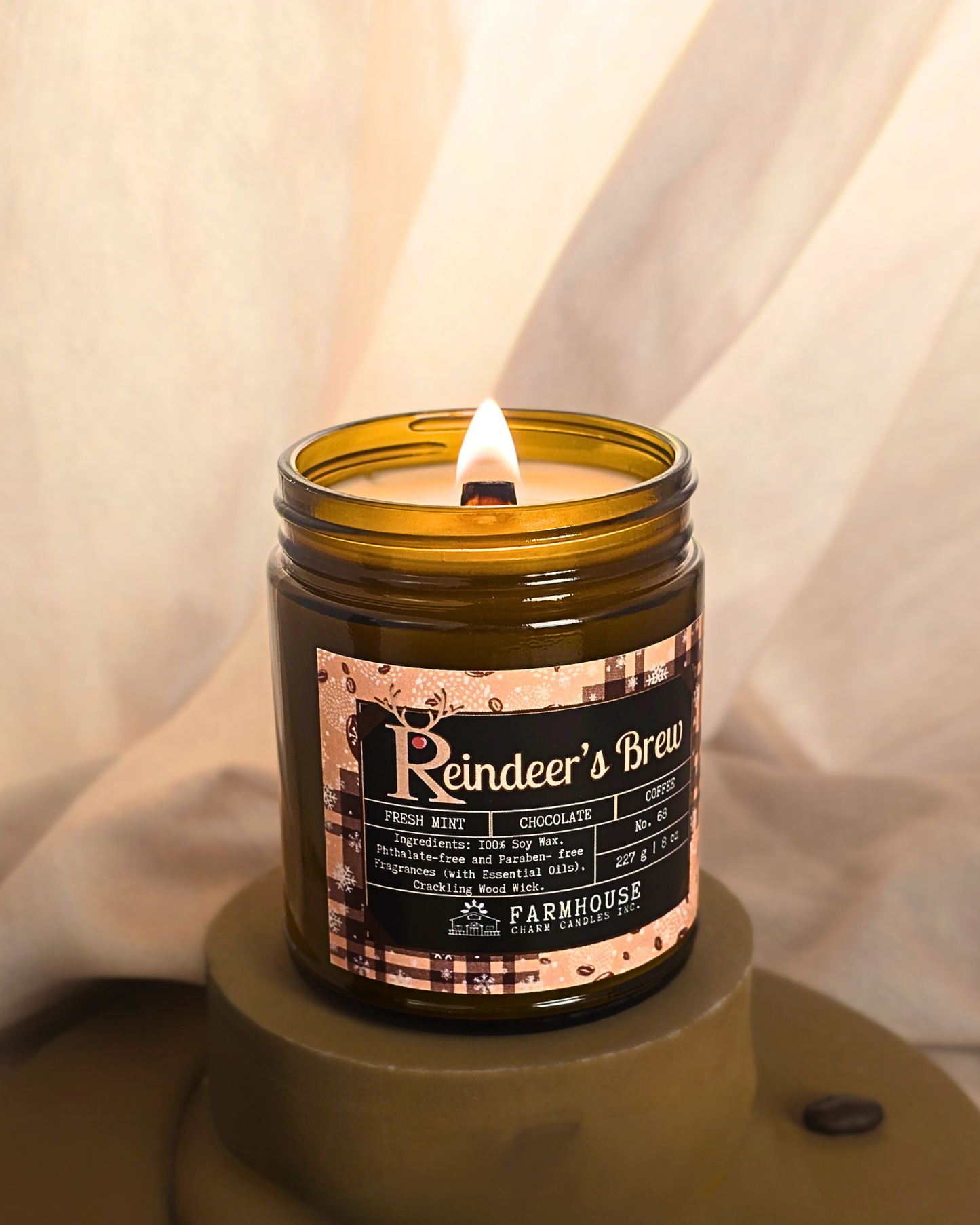 Reindeer’s Brew soy candle in amber jar with warm holiday glow, surrounded by coffee beans, peppermint, and chocolate pieces — cozy Christmas scent from Farmhouse Charm Candles.