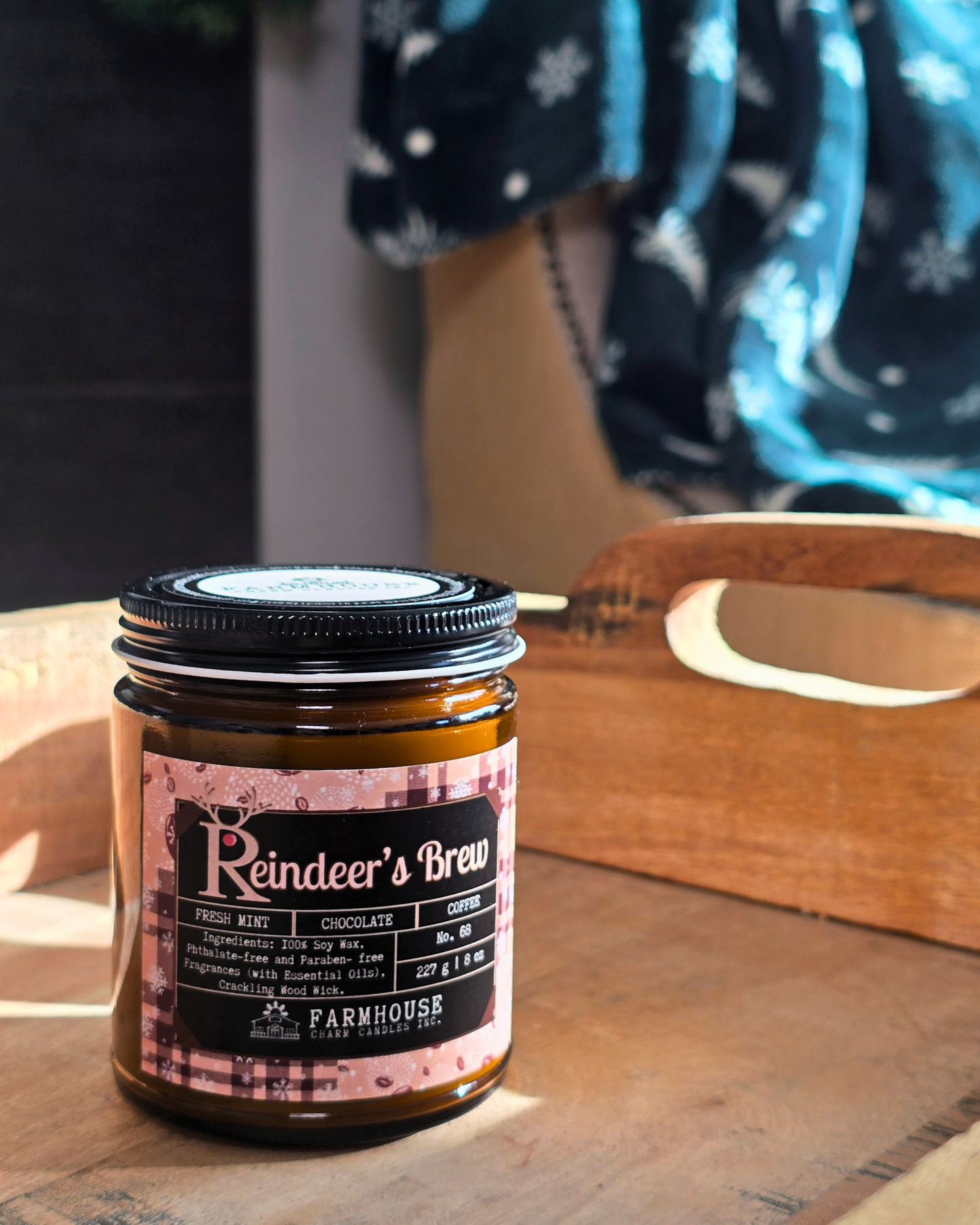 Reindeer’s Brew soy candle in amber jar with warm holiday glow, surrounded by coffee beans, peppermint, and chocolate pieces — cozy Christmas scent from Farmhouse Charm Candles.