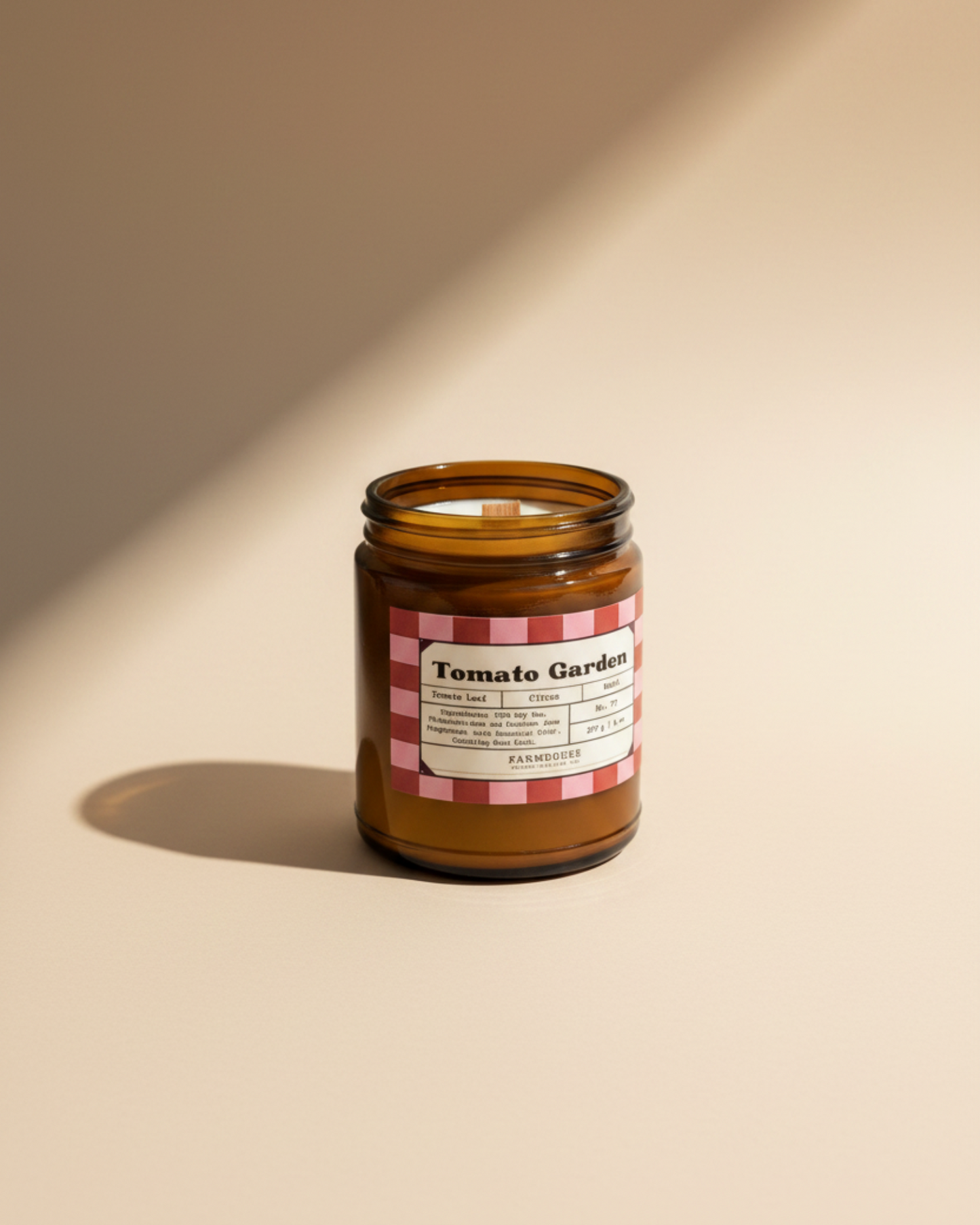 Candle in a jar labeled 'Tomato Garden' by Farmhouse Charm Candles with a checkered design on a beige background