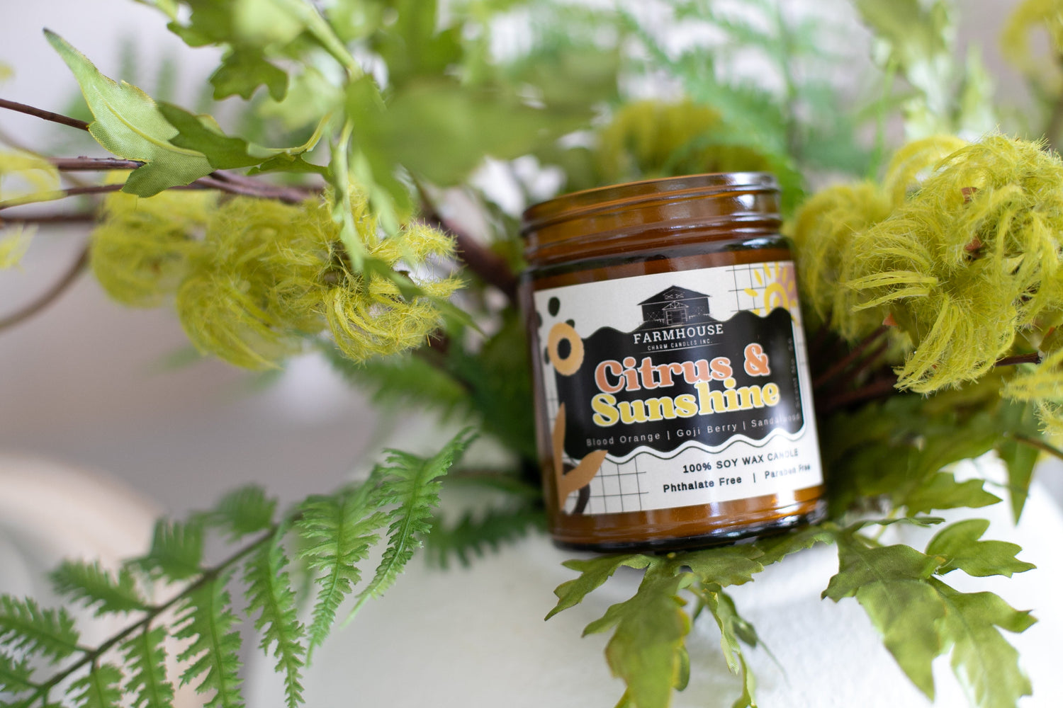 Citrus & Sunshine Soy Wax Candle by Farmhouse Charm Candles on a leafy & bright background.