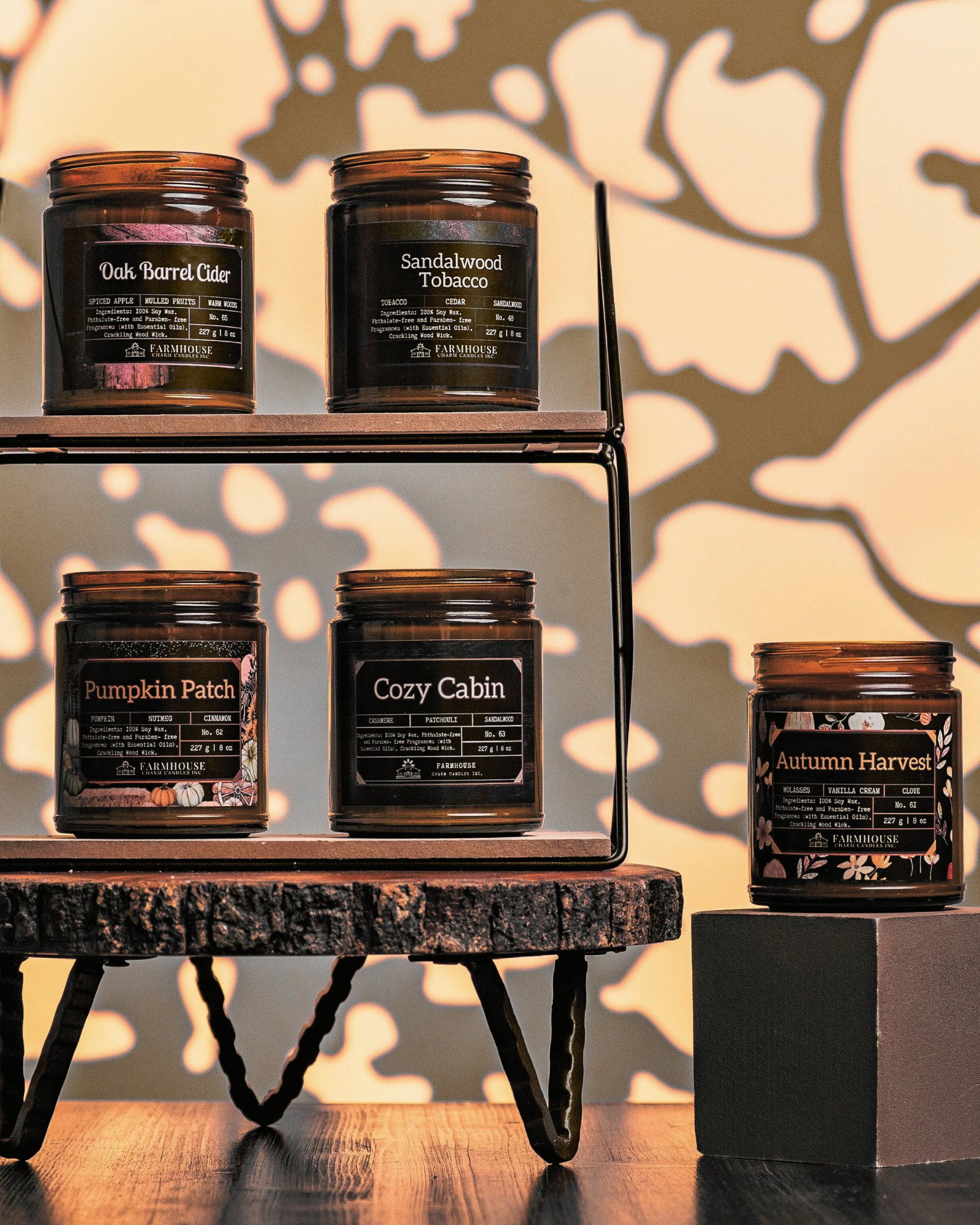 Collection of Autumn Glow Soy candles with labels by Farmhouse Charm Candles on a wooden shelf against a beige background