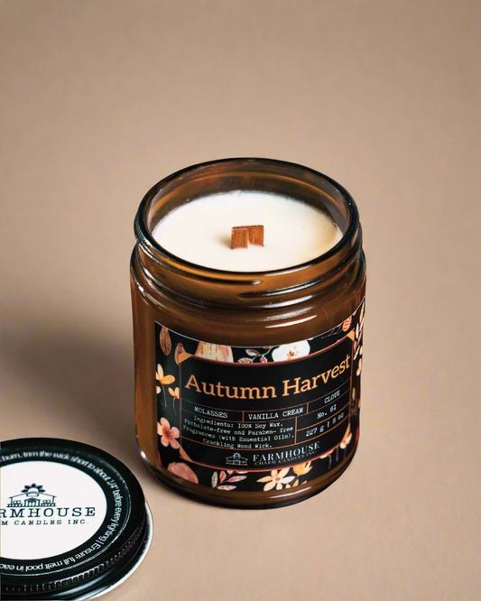 Soy Candle in a glass jar labeled 'Autumn Harvest' by Farmhouse Charm Candles on a beige background