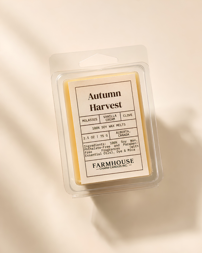 A packaged wax melt product labeled 'Autumn Harvest' by Farmhouse Charm Candles, shown in a clear plastic clamshell package on a warm cream background with soft diagonal shadows.