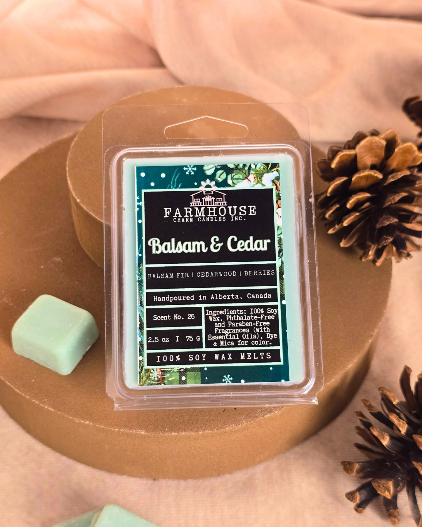 Farmhouse Charm Candles Balsam & Cedar wax melts  on a wooden surface with pinecone.