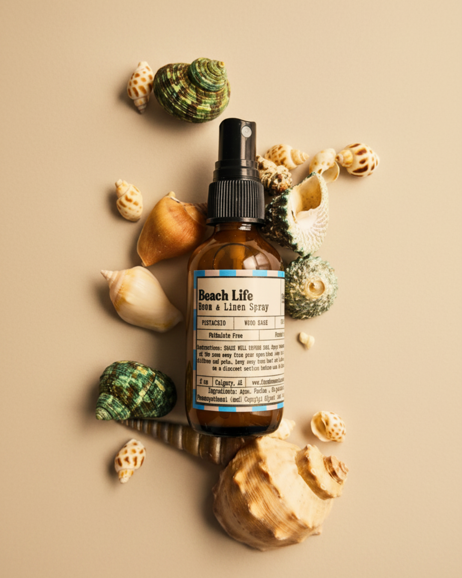 Bottle of 'Beach Life' room and linen spray  by Farmhouse Charm Candles surrounded by seashells on a warm background