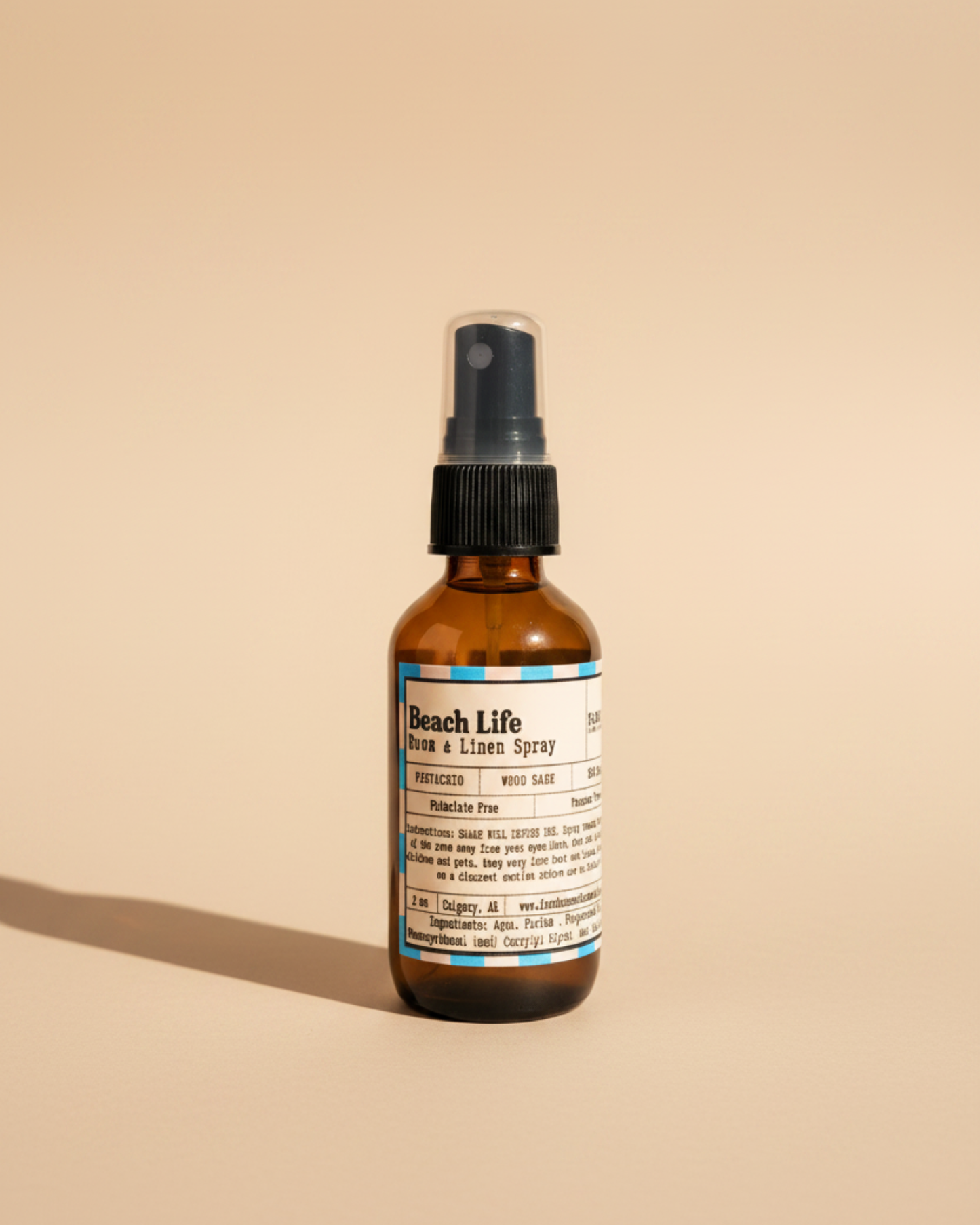 Bottle of Beach Life Room & Linen Spray by Farmhouse Charm Candles on neutral beige background