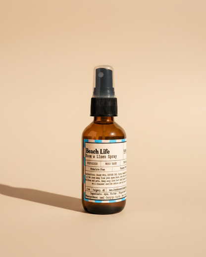 Bottle of Beach Life Room & Linen Spray by Farmhouse Charm Candles on neutral beige background