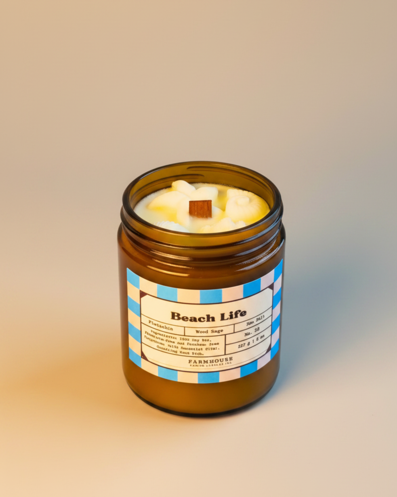 Candle in a brown jar labeled 'Beach Life' by Farmhouse Charm Candle on a textured surface with a neutral background