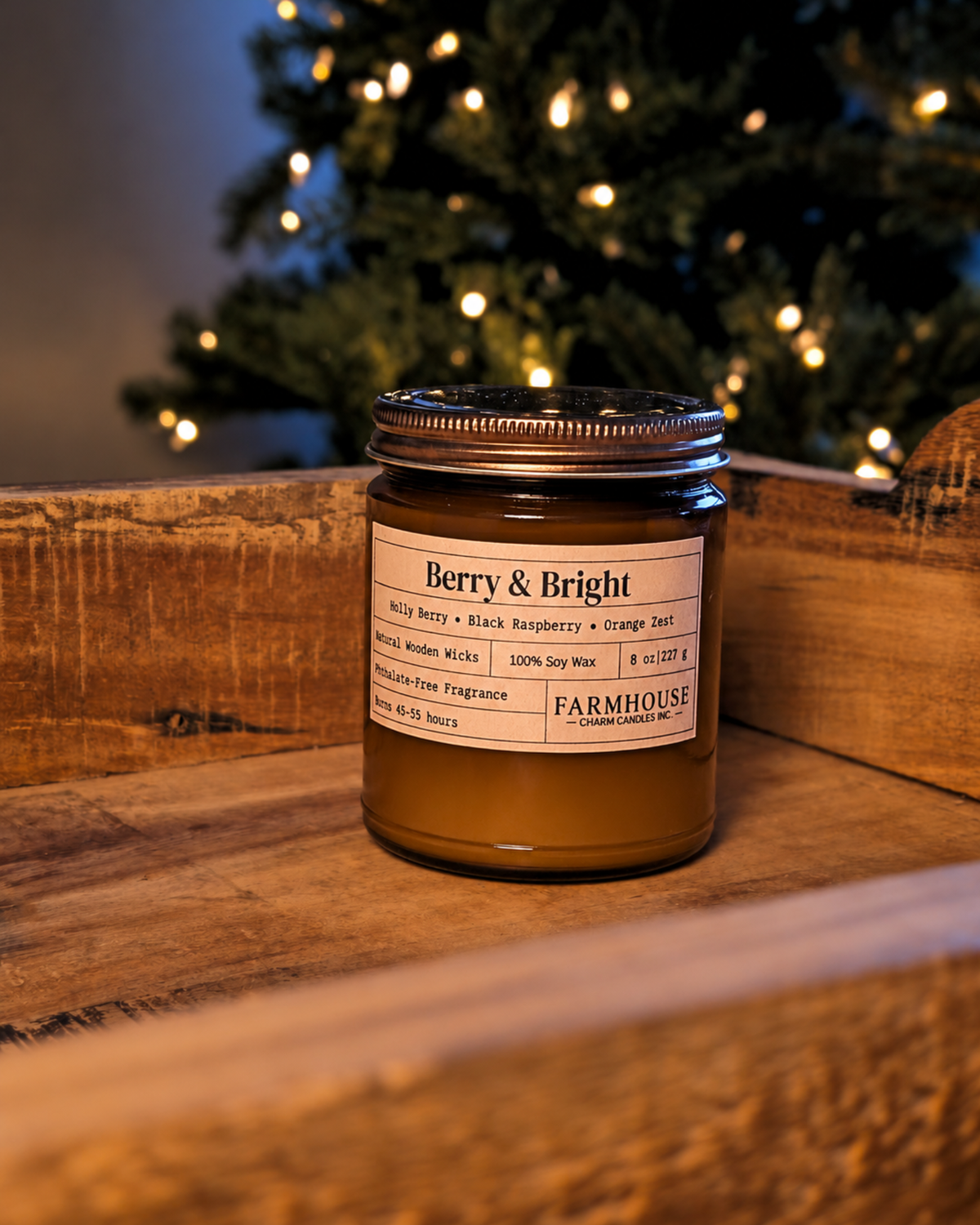 A Farmhouse Charm Candles in a glass jar with a silver metal lid, labeled 'Berry & Bright', sitting on a rustic wooden crate with a blurred Christmas tree in the background.