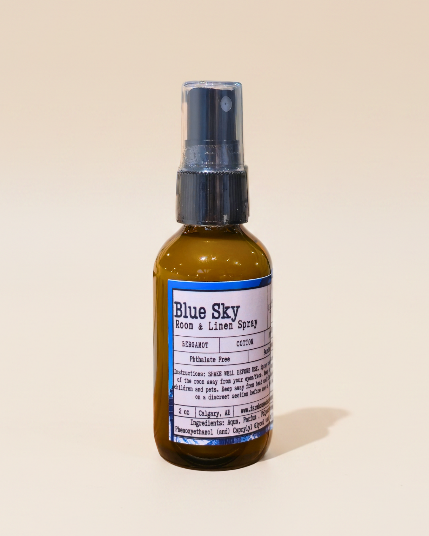 Bottle of Blue Sky room & linen spray by Farmhouse Charm Candles on a beige background
