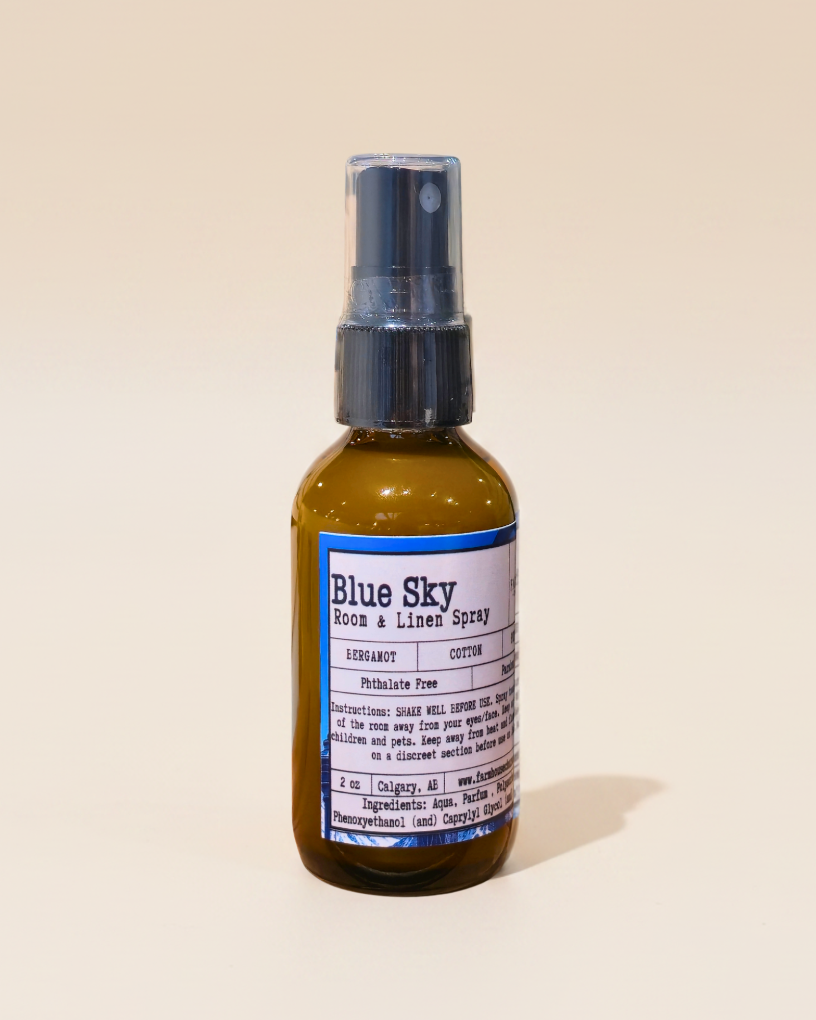 Bottle of Blue Sky room & linen spray by Farmhouse Charm Candles on a beige background