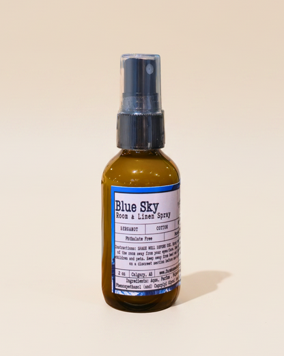 Bottle of Blue Sky room & linen spray by Farmhouse Charm Candles on a beige background