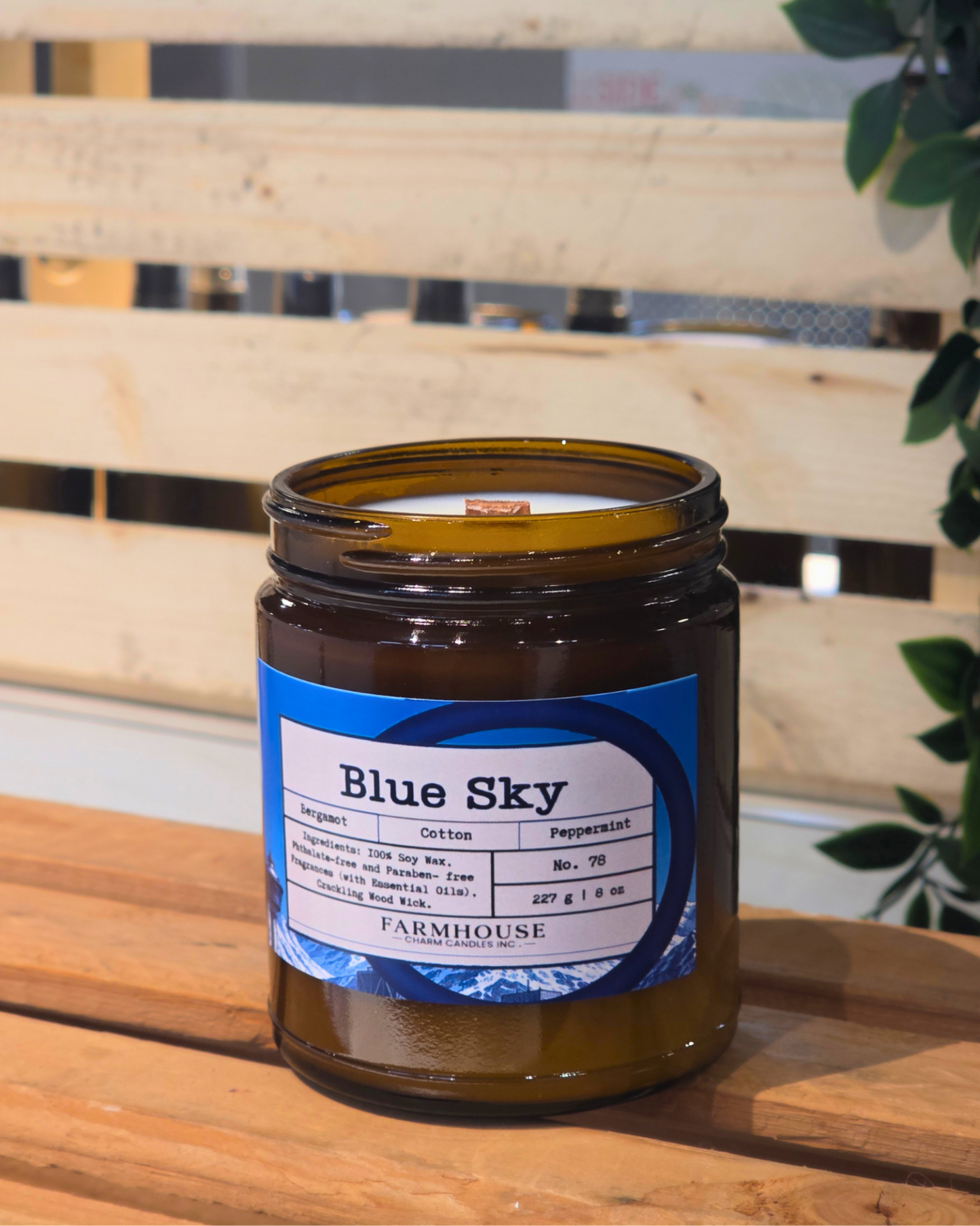 Candle jar labeled 'Blue Sky' by Farmhouse on a wooden surface with a blurred background