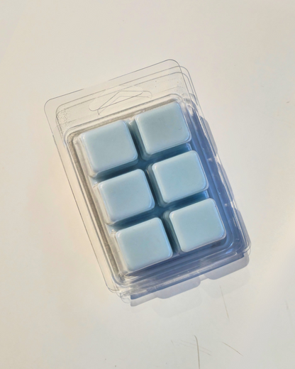 Pack of six light blue wax melts in a clear plastic packaging on a white background
