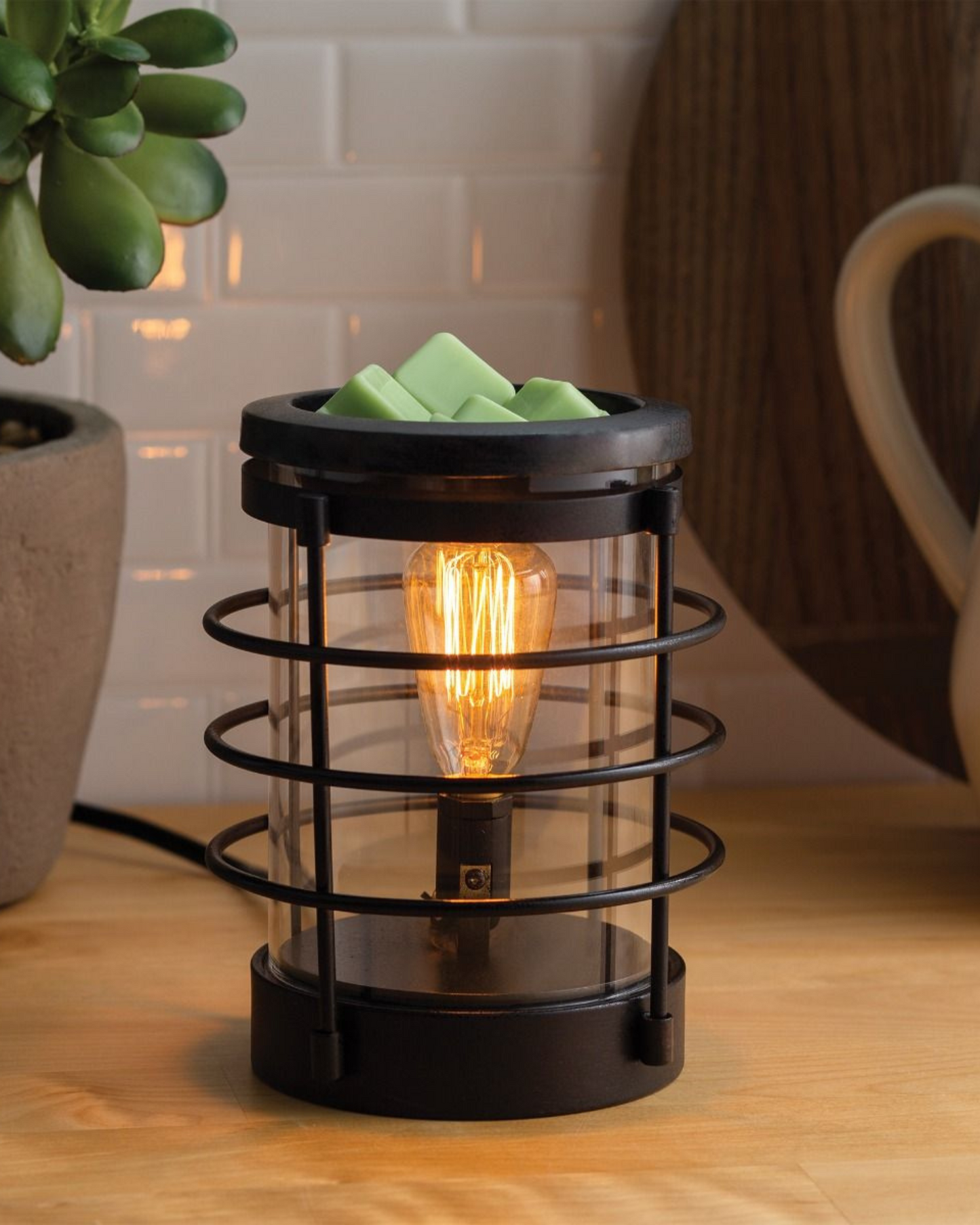 An updated traditional style with wire framing in a matte black finish give this Vintage Bulb Illumination a classic lantern feel. Illumination Fragrance Warmers use a Vintage Bulb to warm wax melts in the dish, releasing their fragrance.   Suggested Use: Simply add wax melts to the dish, turn it on, and enjoy your favorite fragrance as it spreads through the room. This warmer works beautifully with 100% Soy Wax Melts by Farmhouse Charm Candles Inc.