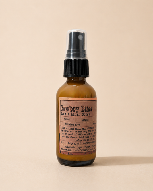 Cowboy Bliss Room and Linen Spray in amber glass bottle with black pump, western-style label showing tobacco and leather scent notes, phthalate-free, made in Calgary Alberta — Farmhouse Charm Candles