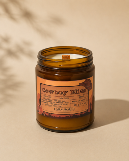  candle in amber jar with wood wick, western label, tobacco/leather/amber notes. cowboy bliss by Farmhouse Charm Candles