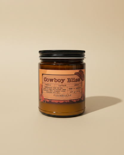  candle in amber jar with wood wick, western label, tobacco/leather/amber notes. Cowboy Bliss by Farmhouse Charm Candles