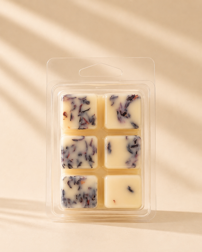 Close-up of 6 cream soy wax melt cubes infused with dried hibiscus petals in clear clamshell packaging, warm beige background — Farmhouse Charm Candles Cowboy Bliss