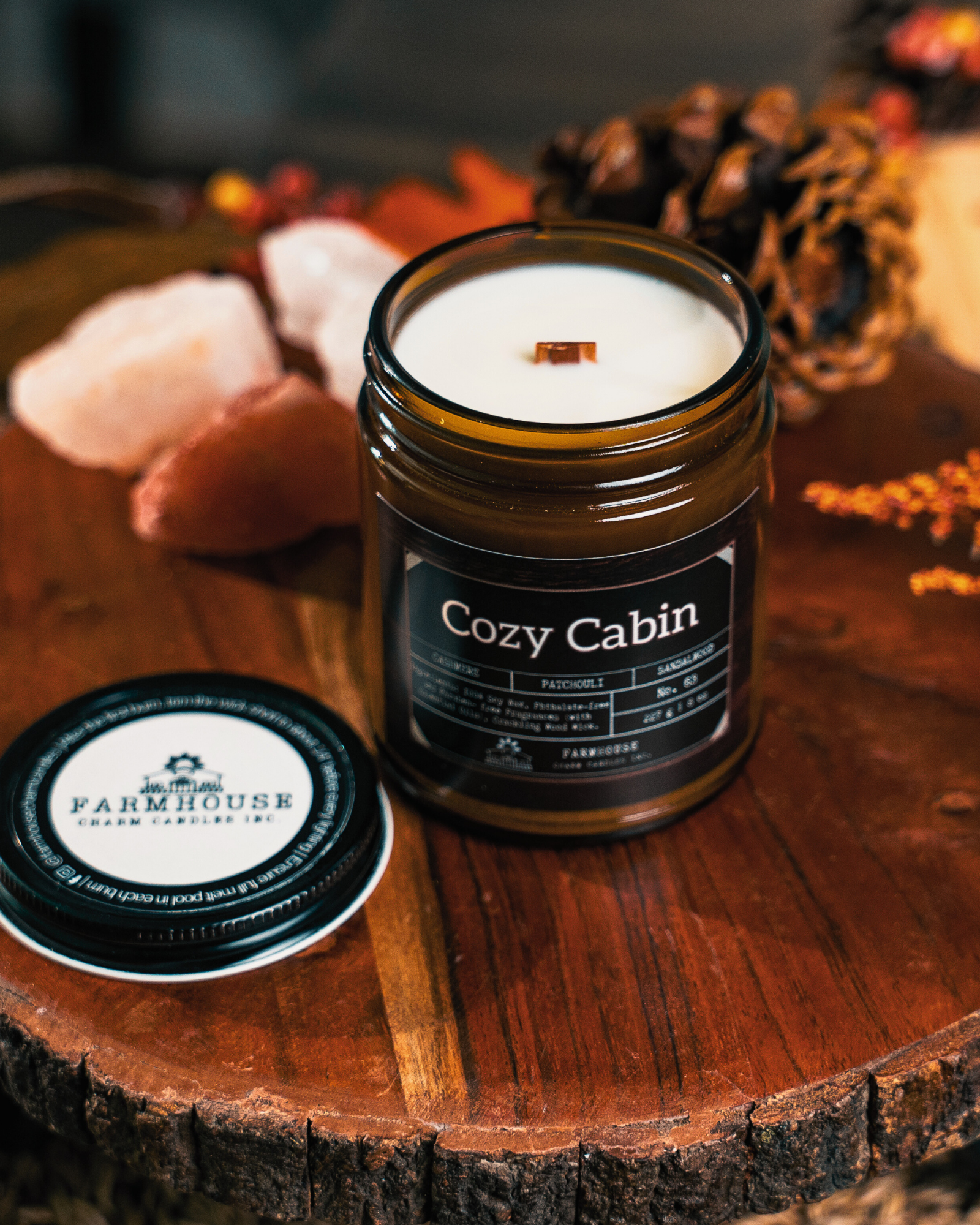 Soy Candle labeled 'Cozy Cabin' by Farmhouse Charm Candles on a wooden surface with decorative elements.