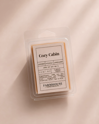 A Farmhouse Charm Candles-  Cozy Cabin 100% soy wax melt in a clear plastic clamshell package, displayed on a warm beige background with soft diagonal shadows.