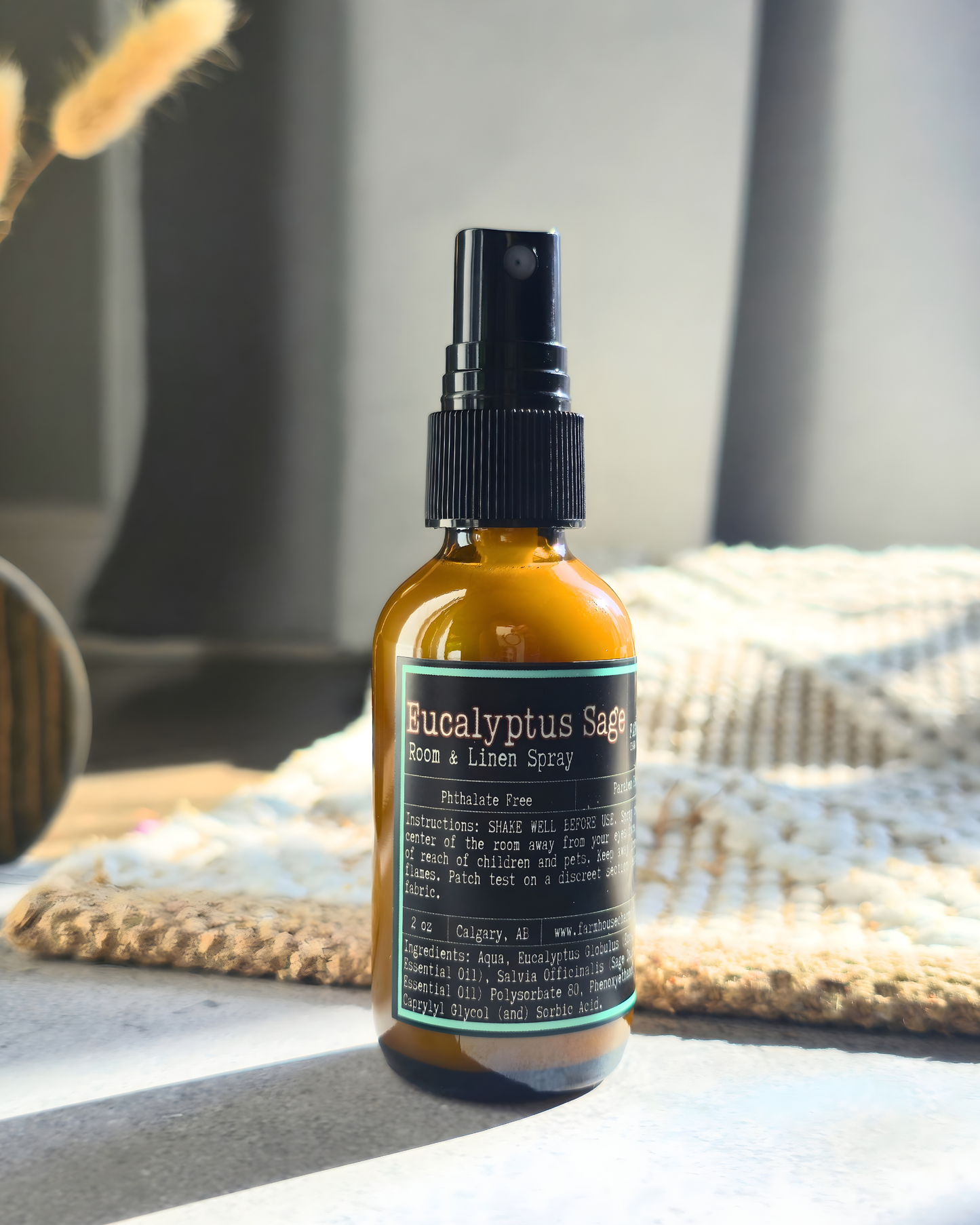 Bottle of Eucalyptus Sage room and linen spray on a textured surface with a blurred background by Farmhouse Charm Candles