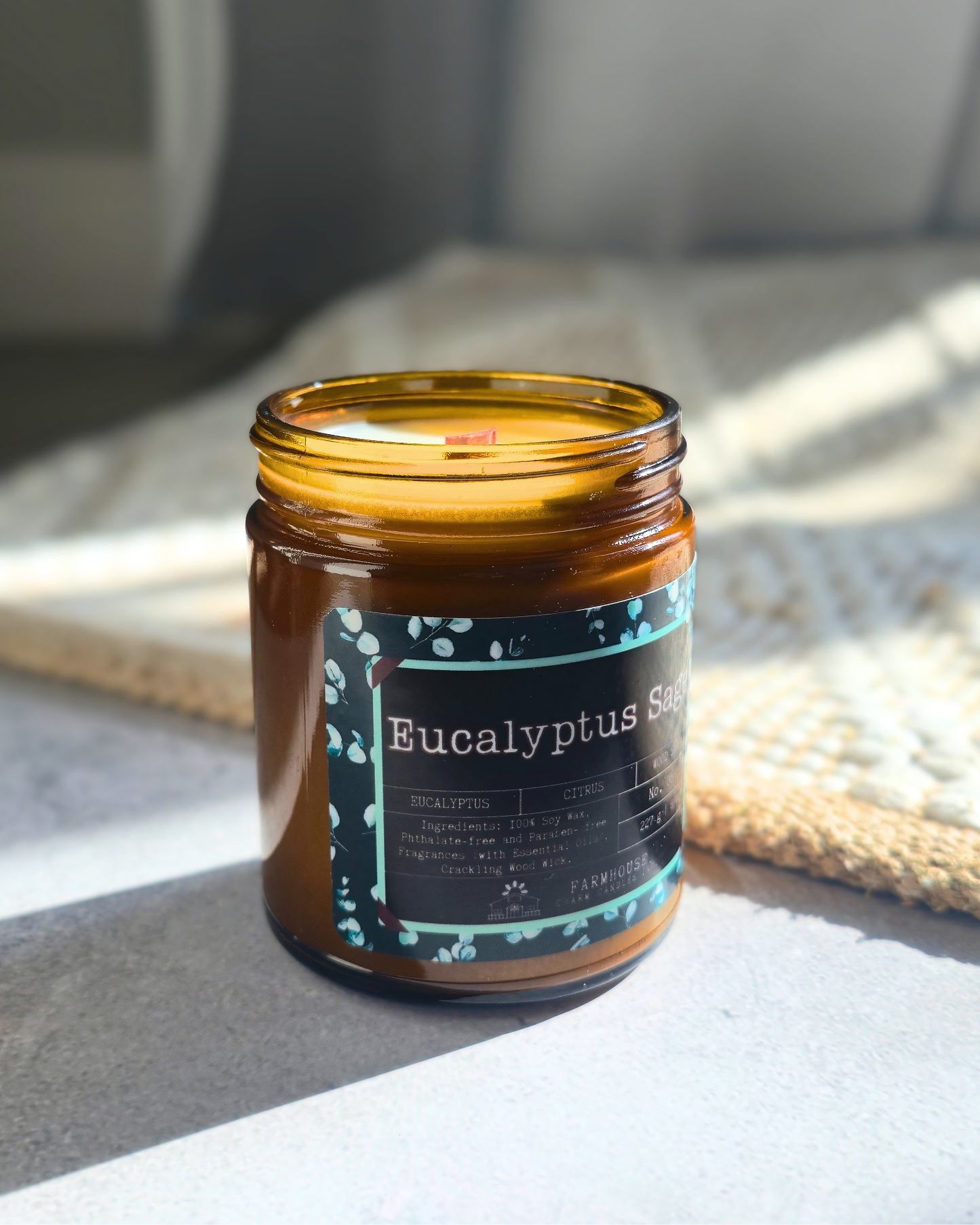 Eucalyptus Sage soy candle by Farmhouse Charm Candles in a glass jar with a label on a light surface.