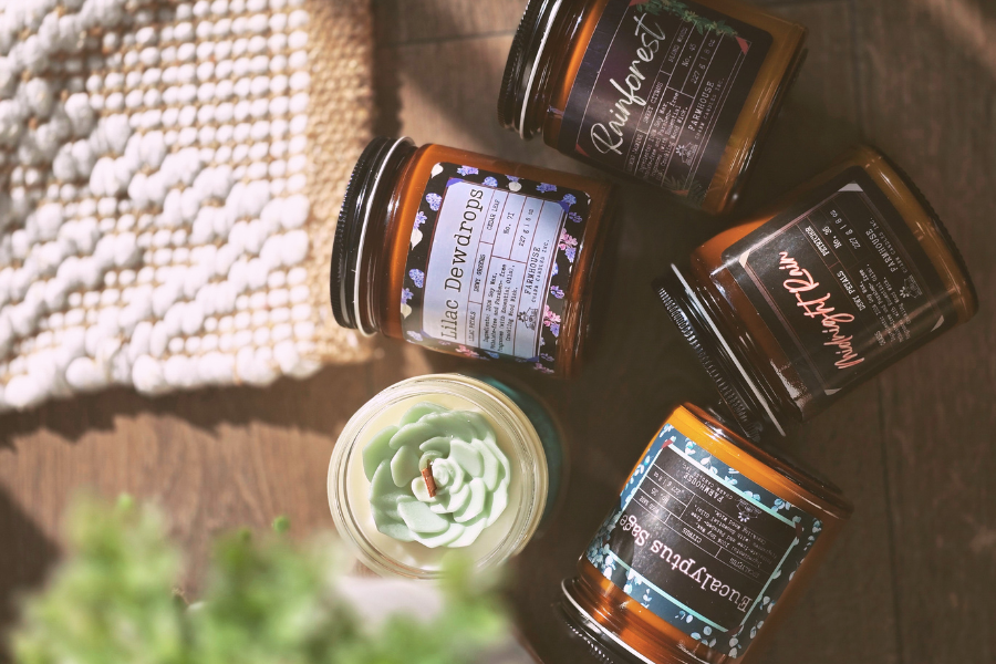 Collection of spring candle jars with labels on a textured surface by Farmhouse Charm Candles