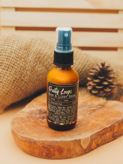 Bottle of Fruity Loops room and linen spray by Farmhouse Charm Candles on a wooden surface with a woven background