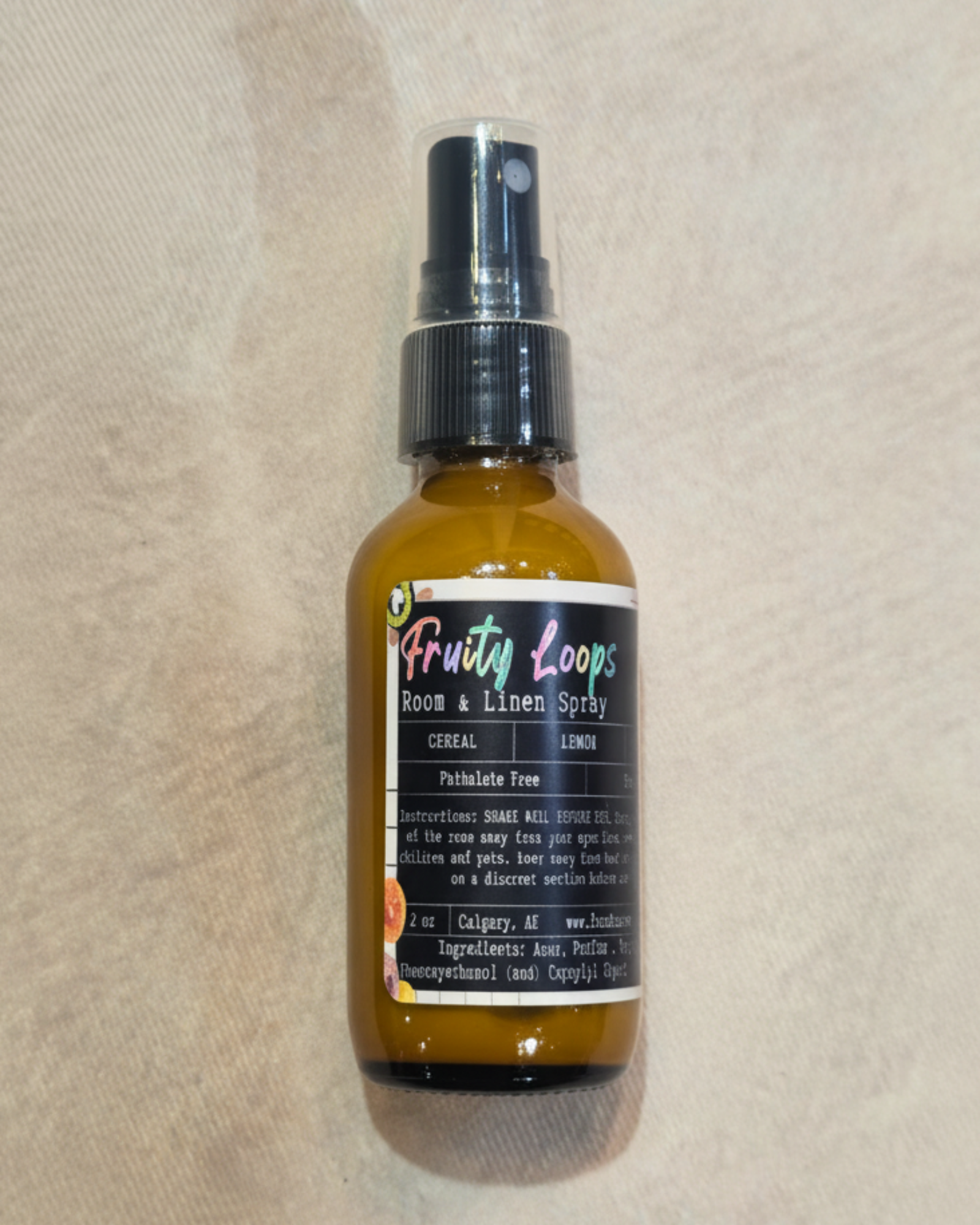 Bottle of 'Fruity Loops' room and linen spray by Farmhouse Charm Candles on a textured beige surface