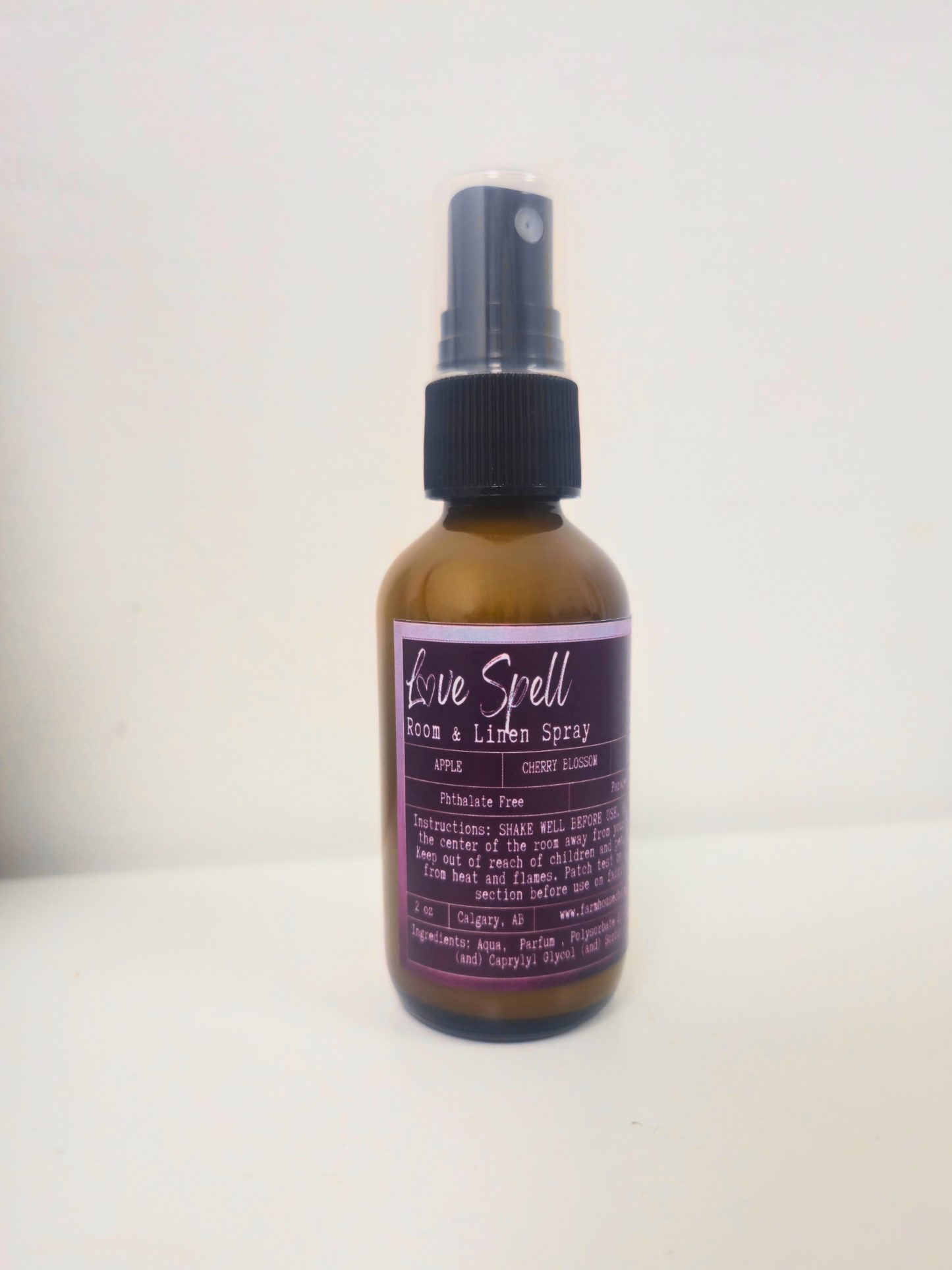 Bottle of 'Love Spell' room and linen  spray by Farmhouse Charm Candles on a white background