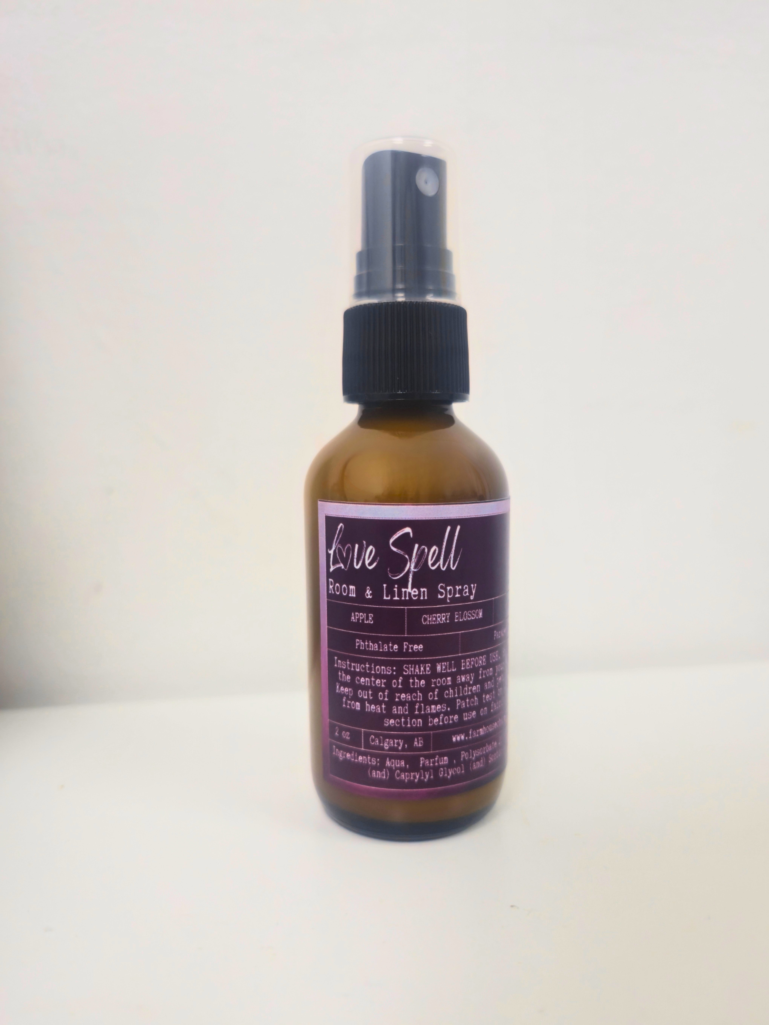 Bottle of 'Love Spell' room and linen  spray by Farmhouse Charm Candles on a white background
