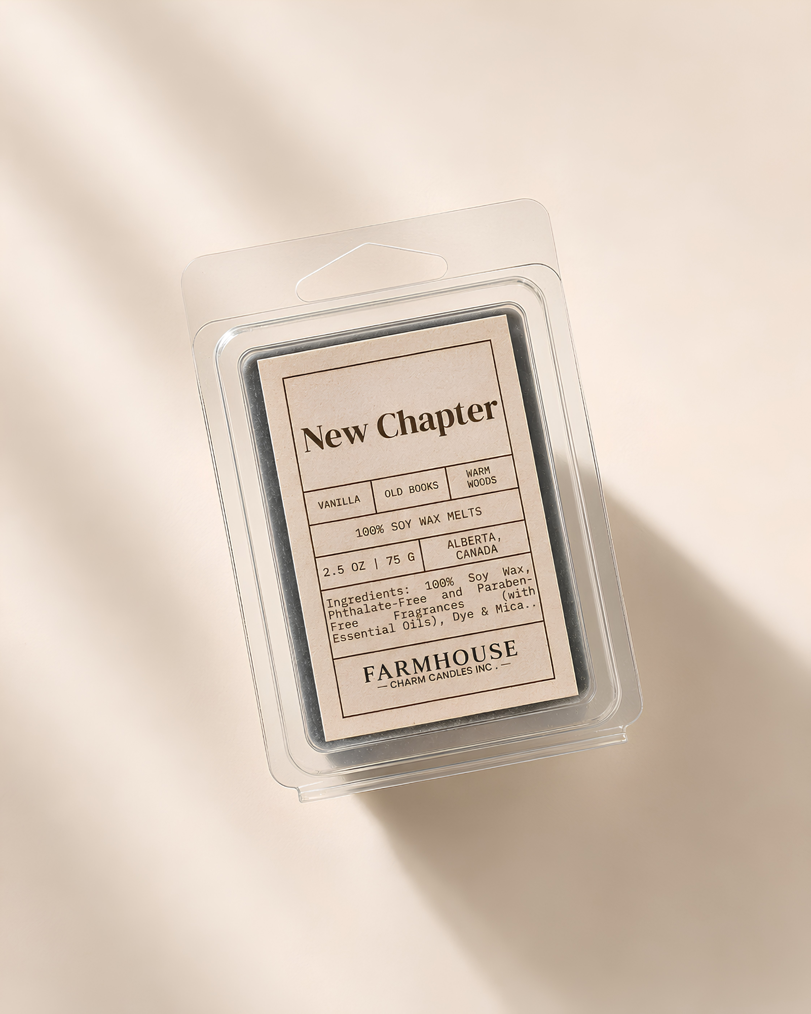 A wax melt package in a clear plastic clamshell container, photographed from above on a warm cream background with soft diagonal shadows. The label reads 'New Chapter' by Farmhouse Charm Candles