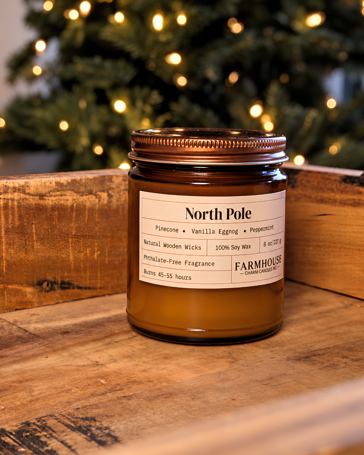 A brown amber glass jar candle with a cream label reading 'North Pole' and Farmhouse Charm Candles set on a rustic wooden surface with a blurred Christmas tree and warm lights in the background.