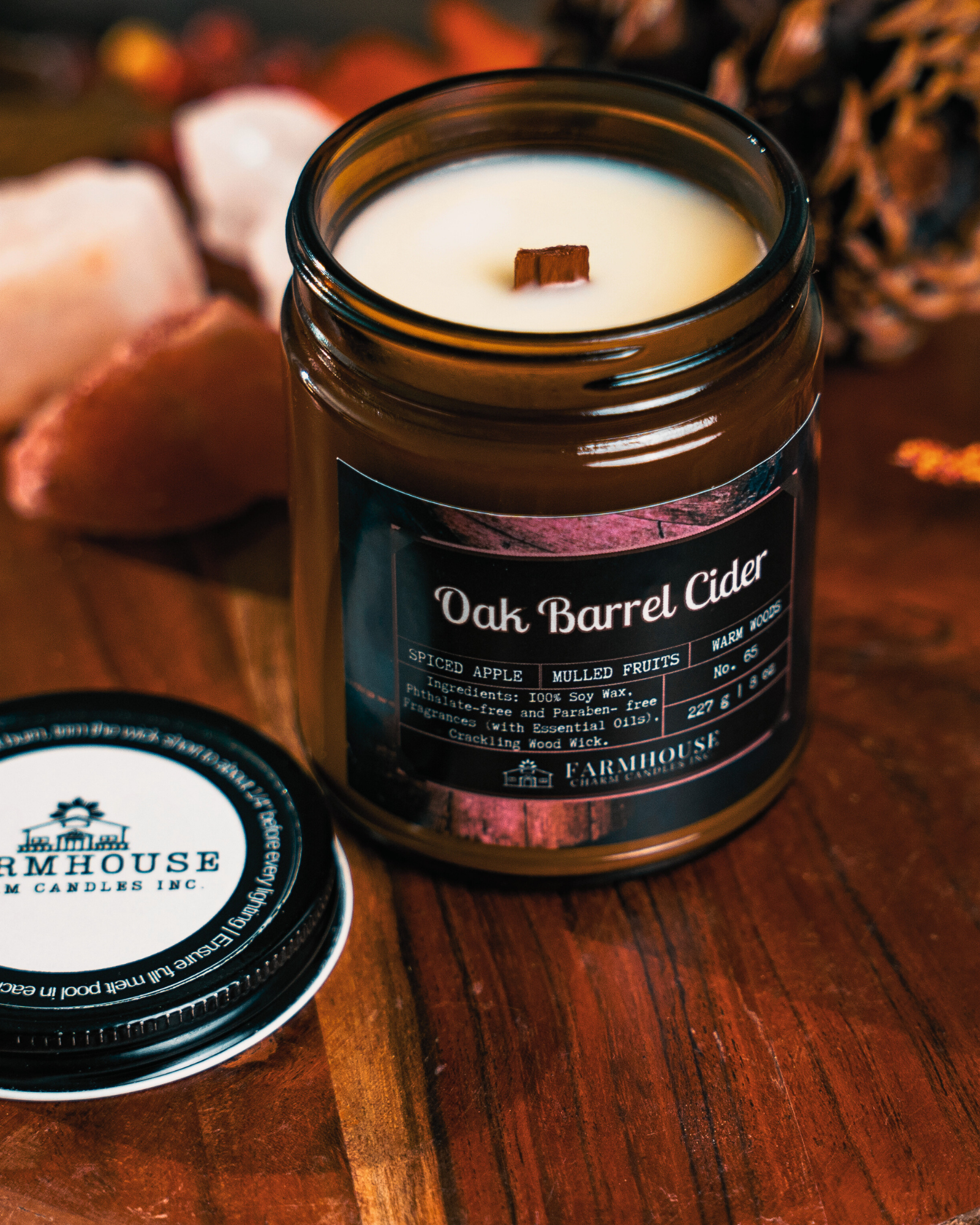 Soy Candle in a jar labeled 'Oak Barrel Cider' on a wooden surface with 'Farmhouse Candles Inc.' branding.