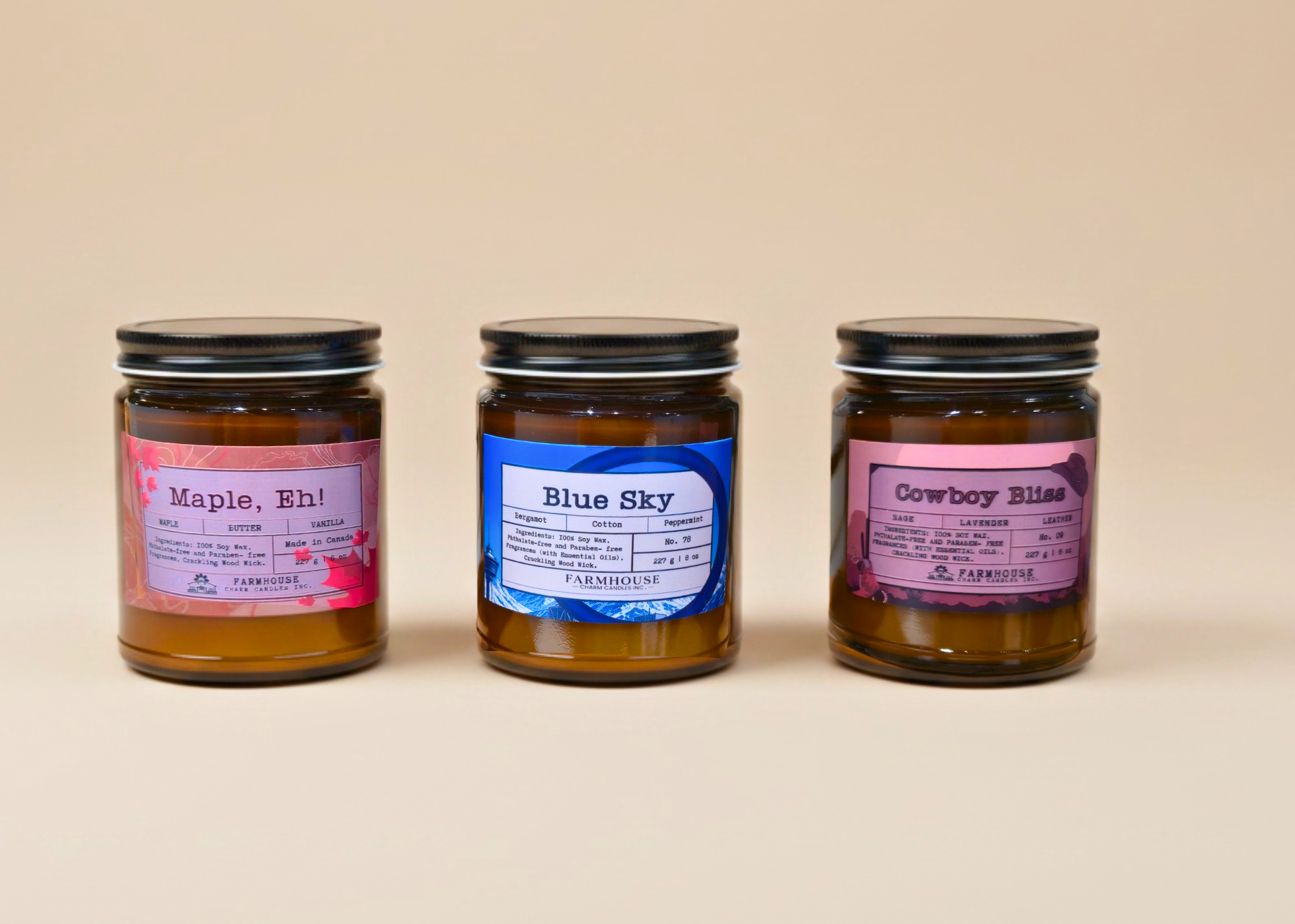 Three jars of candles by Farmhouse Charm Candles with labeled scents (Maple, Eh, Blue Sky and Cowboy Bliss  on a beige background