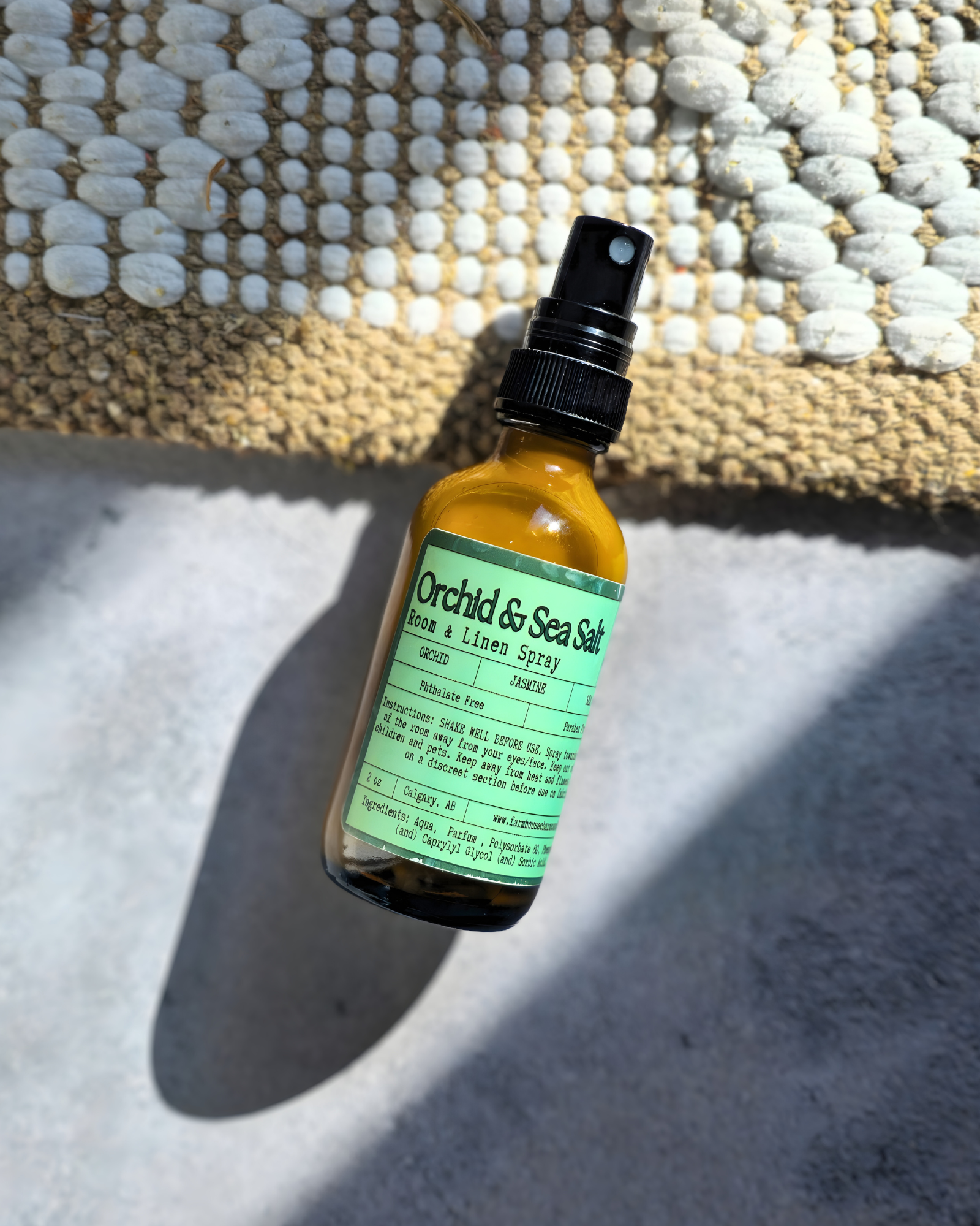 Bottle of Orchid & Sea Salt room & linen spray on a textured surface by  Farmhouse Charm Candles