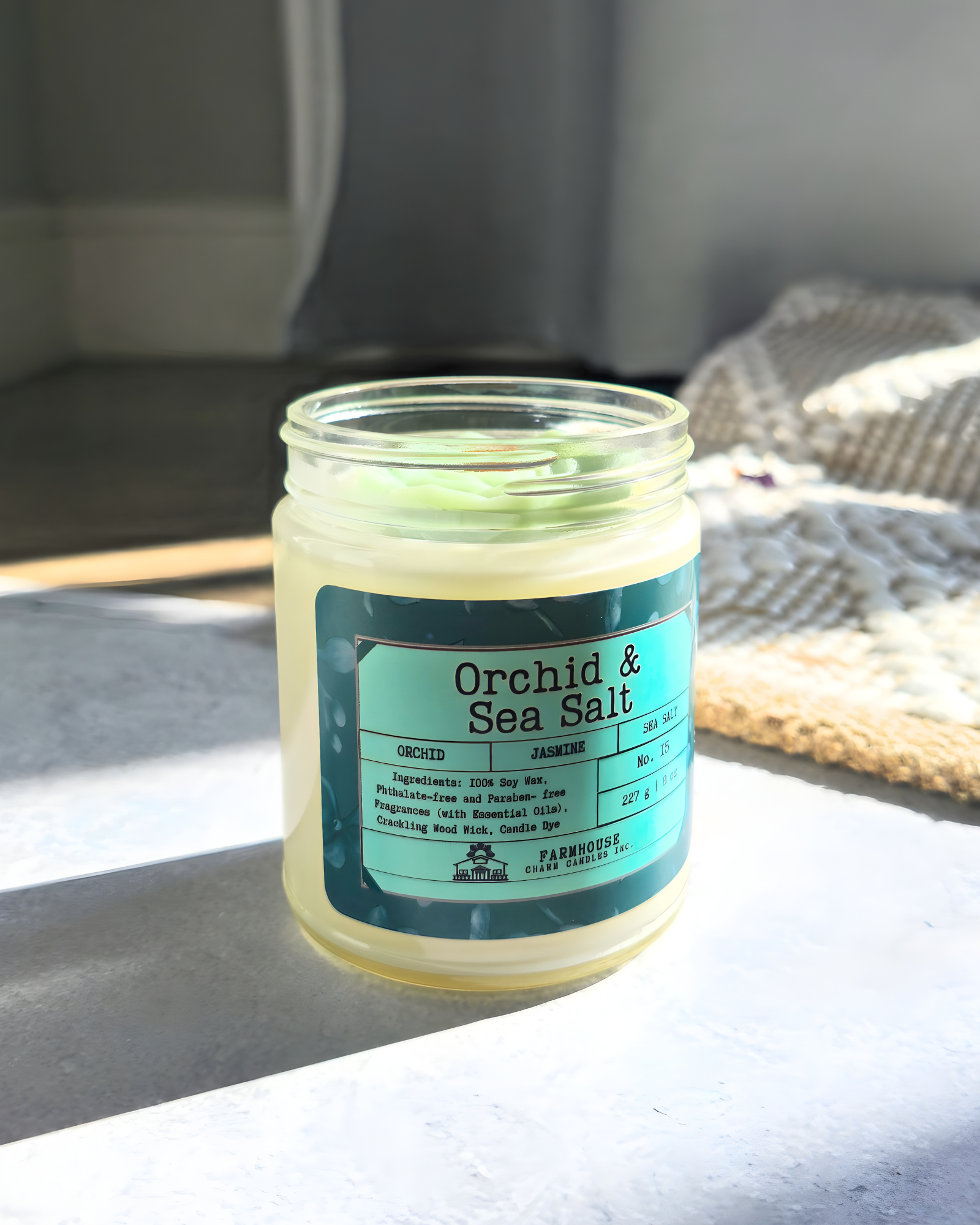 Jar of orchid and sea salt soy candle on a surface with a blurred background  by Farmhouse Charm Candles