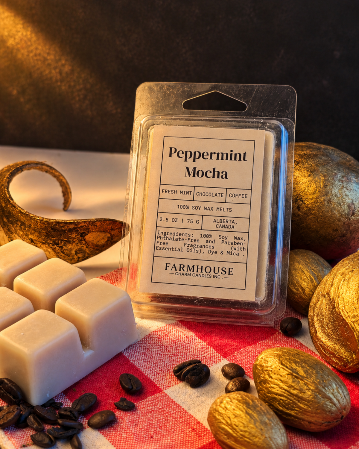 A packaged wax melt labeled 'Peppermint Mocha' by Farmhouse Charm Candles stands on a red-and-white check cloth with coffee beans, cream-colored wax cubes, and gold-toned decorative elements around it.