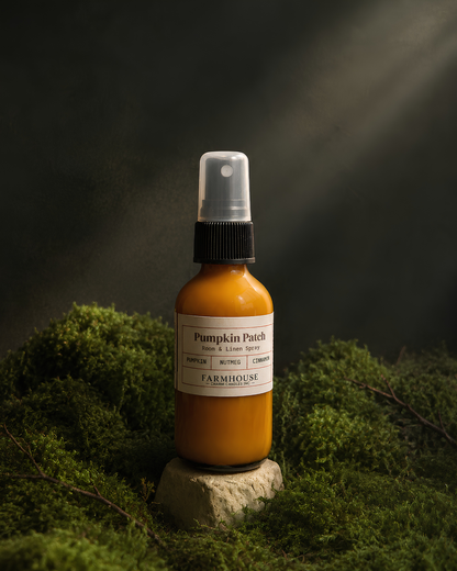 A spray bottle of Pumpkin Patch room and linen spray by  Farmhouse Charm Candles filled with  liquid and resting on a small stone pedestal amidst green moss under dramatic light beams.