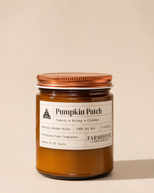 A candle in an amber glass jar with a copper-toned metal lid and a white paper label. The label reads 'Pumpkin Patch' with scent notes of pumpkin, nutmeg, and cinnamon, and shows the brand Farmhouse Charm Candles.