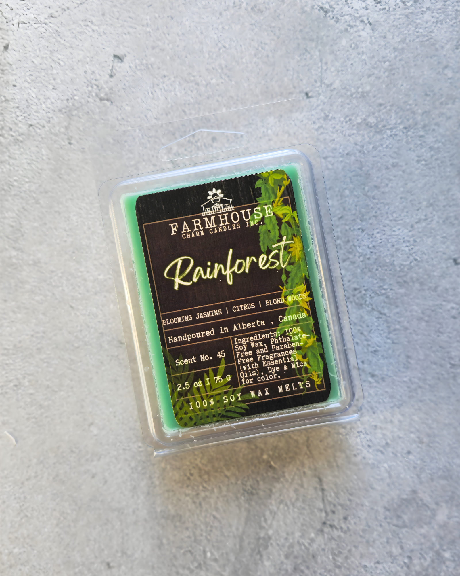 Packaged wax melt with 'Farmhouse Charm Candles' branding on a gray surface. Rainforest Soy Wax Melts